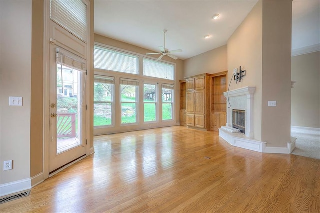 unfurnished living room with visible vents, a ceiling fan, plenty of natural light, and a high end fireplace
