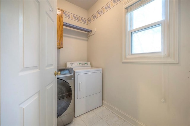 laundry room with light tile patterned floors, baseboards, cabinet space, and washer and clothes dryer