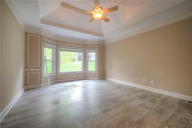 spare room with a ceiling fan, visible vents, crown molding, baseboards, and a raised ceiling