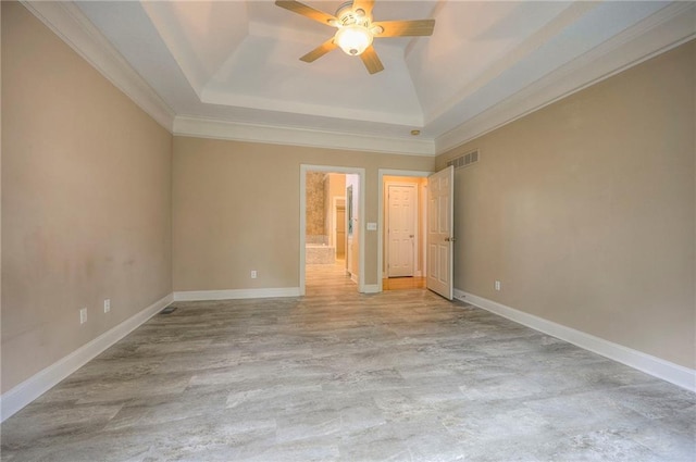 unfurnished bedroom featuring crown molding, visible vents, baseboards, a raised ceiling, and a ceiling fan