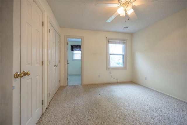 unfurnished bedroom with ceiling fan, carpet, a textured ceiling, and visible vents