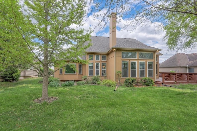 back of house featuring stucco siding, a wooden deck, a yard, and a chimney