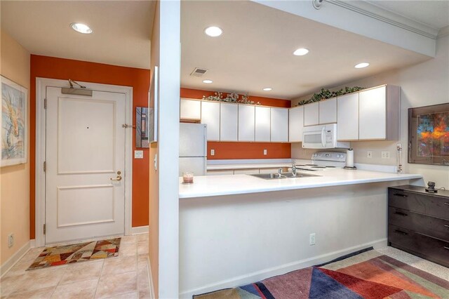 4949 Wornall Rd Unit 203, Kansas City, MO 64112 - kitchen with white appliances, a peninsula, light countertops, recessed lighting, and white cabinets