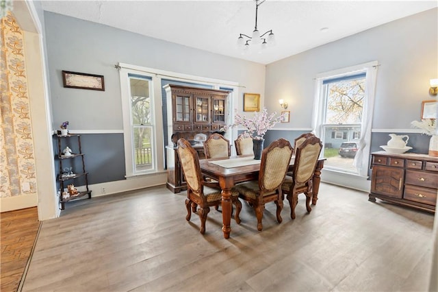 dining space with baseboards, wood finished floors, and an inviting chandelier