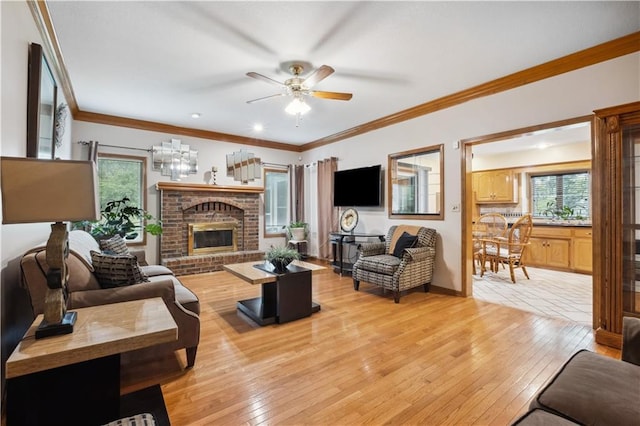 living area featuring a ceiling fan, light wood-style flooring, a brick fireplace, and a wealth of natural light