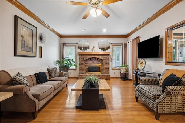 living room with ceiling fan, ornamental molding, light wood-style flooring, and a fireplace