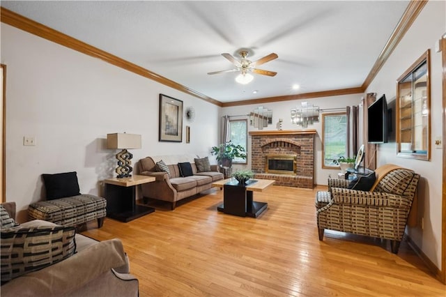 living area featuring crown molding, a ceiling fan, light wood-style flooring, and a fireplace