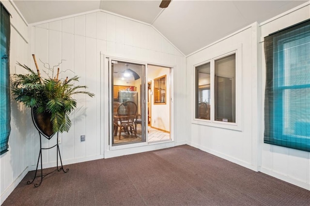 exterior space with a decorative wall, vaulted ceiling, and dark colored carpet