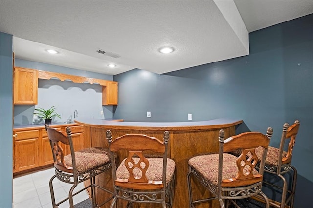 bar with indoor bar, recessed lighting, a textured ceiling, and visible vents