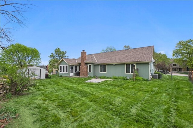 rear view of house with central AC, a fenced backyard, a chimney, a lawn, and an outdoor structure