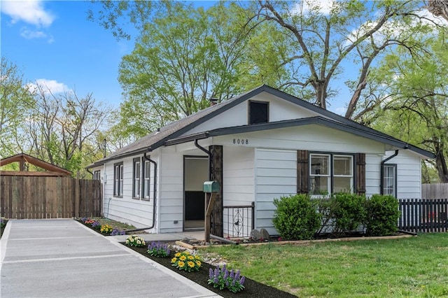bungalow-style house with a front lawn and fence