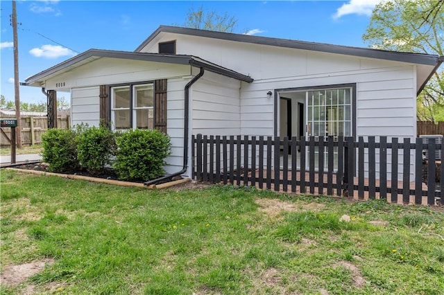 view of home's exterior featuring a lawn and fence