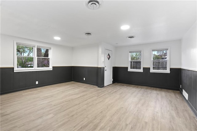 unfurnished room featuring visible vents, a wainscoted wall, and wood finished floors