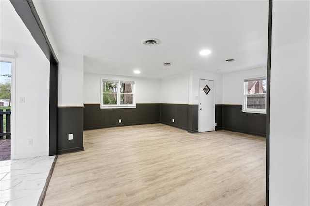 empty room featuring recessed lighting, a wainscoted wall, visible vents, and light wood-style flooring