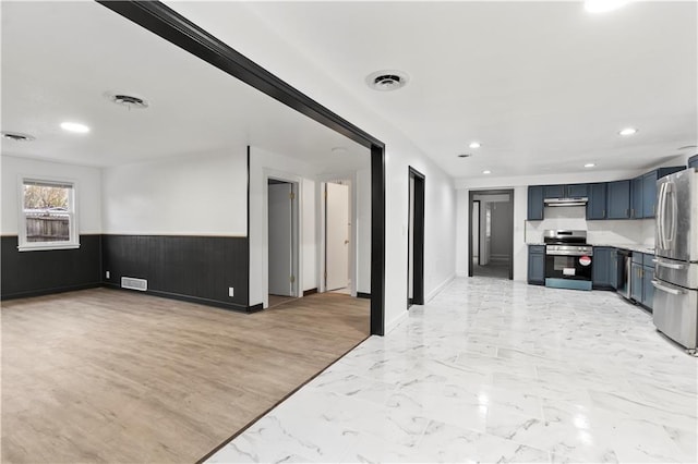 interior space with blue cabinets, open floor plan, stainless steel appliances, light countertops, and visible vents