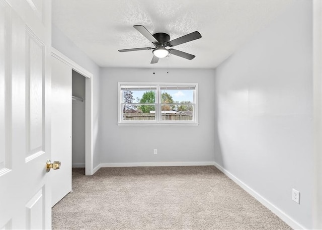 unfurnished bedroom featuring a textured ceiling, a closet, ceiling fan, carpet floors, and baseboards