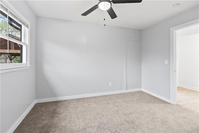 carpeted empty room with baseboards and a ceiling fan