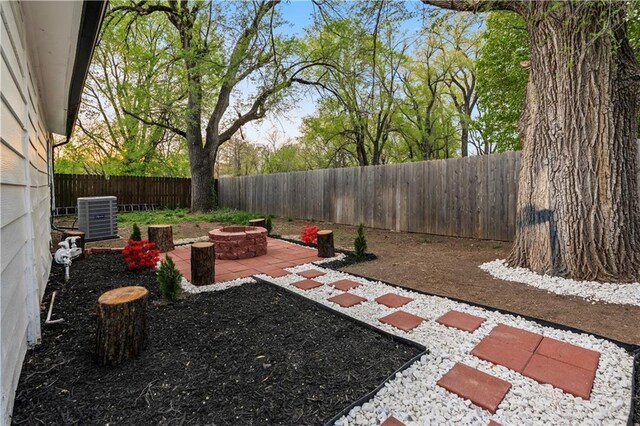 view of yard featuring central AC, a patio area, a fenced backyard, and an outdoor fire pit