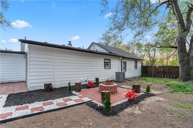 rear view of house with cooling unit, a fenced backyard, a patio, and a fire pit