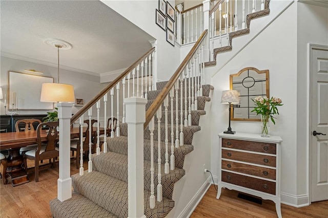 stairs featuring crown molding, baseboards, and wood finished floors