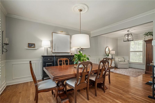 dining space with crown molding, wainscoting, and wood finished floors