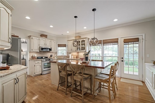 kitchen with light wood-style floors, a kitchen breakfast bar, stainless steel appliances, tasteful backsplash, and glass insert cabinets