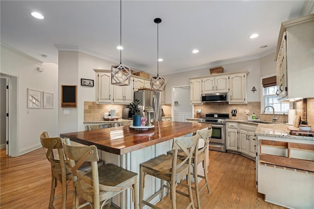 kitchen featuring a sink, wooden counters, stainless steel appliances, decorative backsplash, and ornamental molding