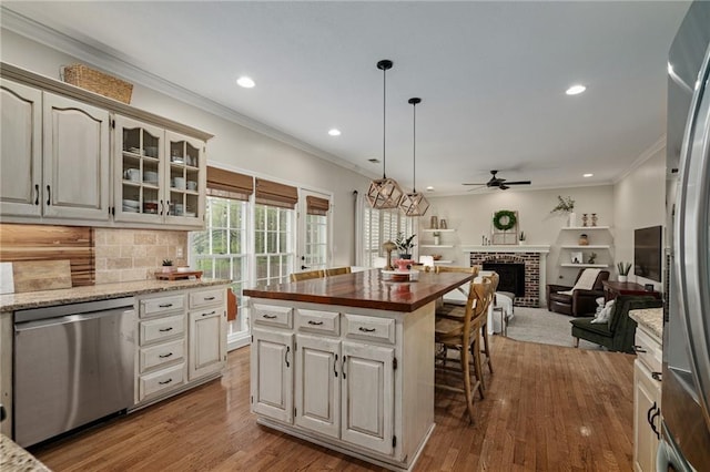 kitchen featuring ornamental molding, glass insert cabinets, recessed lighting, a ceiling fan, and stainless steel appliances