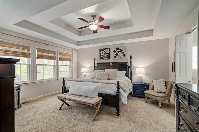 bedroom with light colored carpet, a ceiling fan, and a tray ceiling