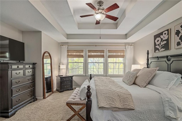 carpeted bedroom with baseboards, a ceiling fan, and a tray ceiling