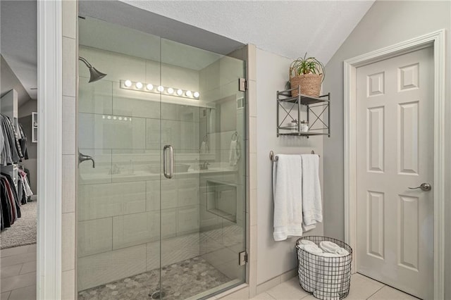 full bath featuring tile patterned floors, baseboards, lofted ceiling, a spacious closet, and a stall shower