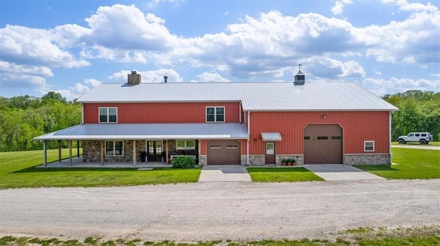view of front of property featuring a front lawn, a chimney, driveway, a porch, and stone siding