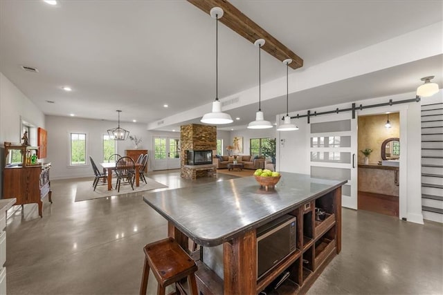 kitchen with stainless steel countertops, finished concrete flooring, a barn door, recessed lighting, and baseboards