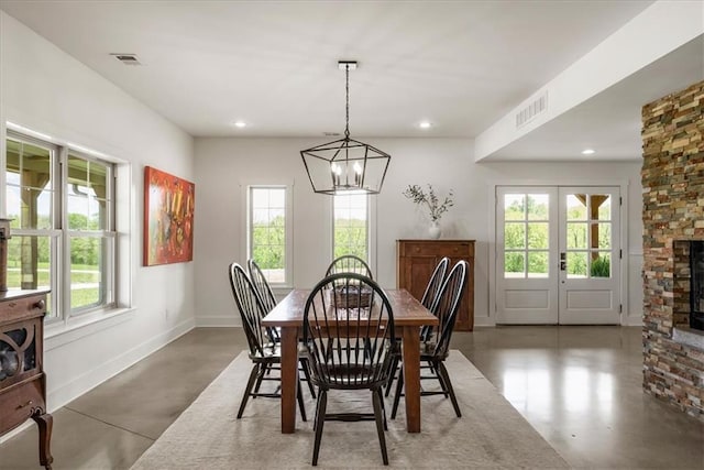 dining area featuring concrete floors, plenty of natural light, a stone fireplace, and recessed lighting