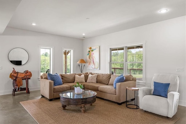 living room featuring plenty of natural light, finished concrete flooring, recessed lighting, and baseboards