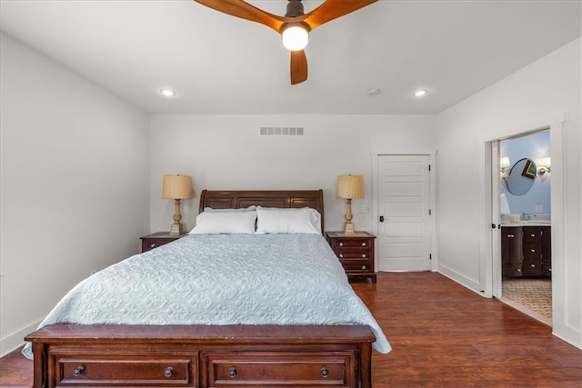 bedroom featuring dark wood finished floors, a sink, baseboards, recessed lighting, and ensuite bath