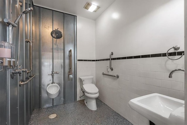 bathroom featuring a stall shower, speckled floor, a sink, toilet, and tile walls