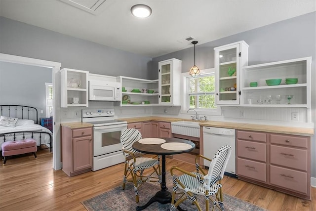 kitchen with open shelves, white appliances, a sink, hanging light fixtures, and light wood finished floors