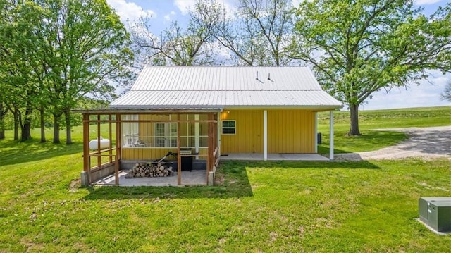 rear view of house featuring a yard, a patio, and metal roof