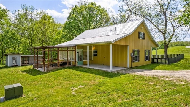 back of property with an outdoor structure, dirt driveway, a patio, a shed, and metal roof