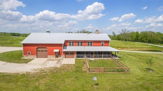 back of property with metal roof, a yard, driveway, and a chimney