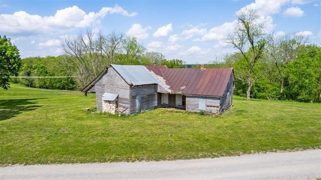 view of side of property featuring a lawn, a barn, metal roof, and an outdoor structure