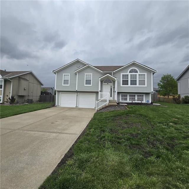split foyer home featuring a garage, fence, a front lawn, and driveway
