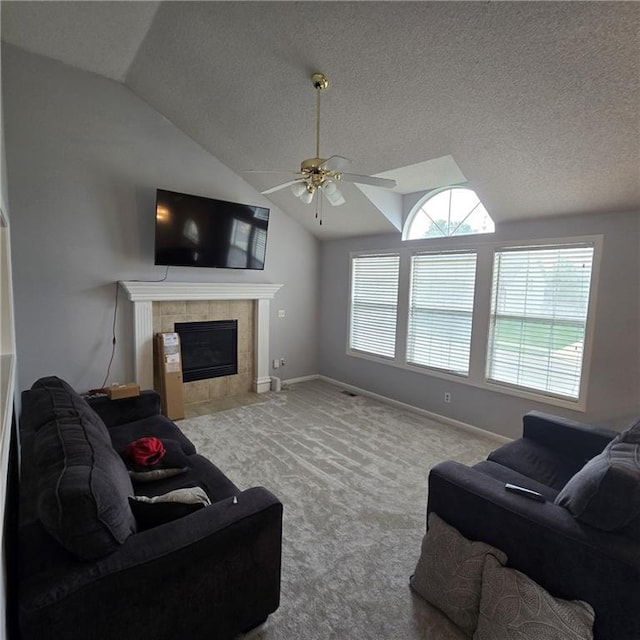 living room with a tile fireplace, carpet floors, ceiling fan, baseboards, and lofted ceiling