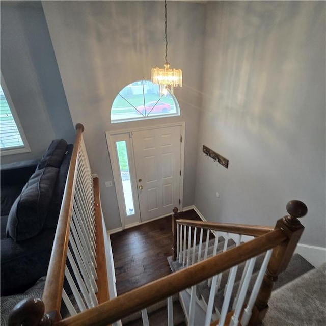 entryway featuring wood finished floors, stairs, baseboards, a notable chandelier, and a towering ceiling