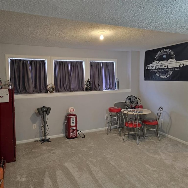 rec room featuring a textured ceiling, carpet flooring, and baseboards