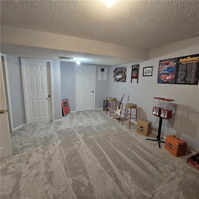 rec room featuring baseboards, visible vents, a textured ceiling, and carpet