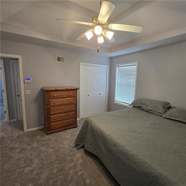 bedroom with a closet, carpet, visible vents, a ceiling fan, and a tray ceiling