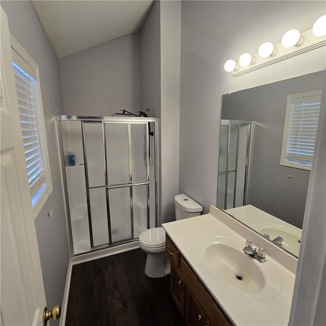 full bath featuring toilet, wood finished floors, vanity, and a stall shower