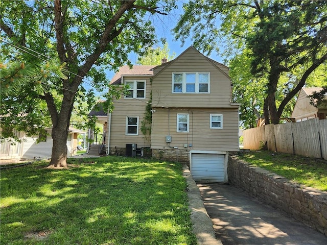 back of property with concrete driveway, an attached garage, and central AC unit